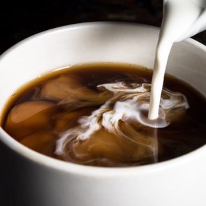 close up of milk being poured into a cup of coffee