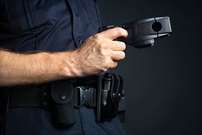 cropped shot of police officer holding taser stun gun