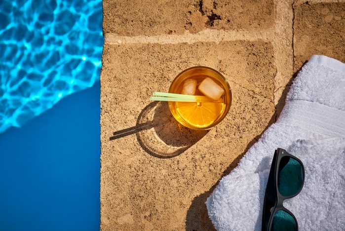 cocktail by the pool with towel and sunglasses overhead