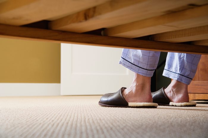 man's feet in slippers shot from under the bed