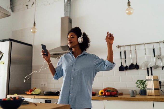 woman listening to music and dancing in kitchen at home
