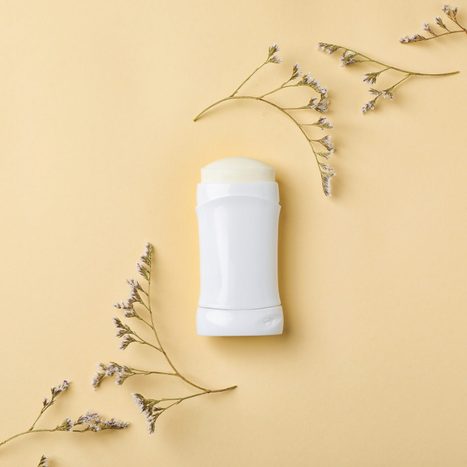 white deodorant stick on yellow background with flowers