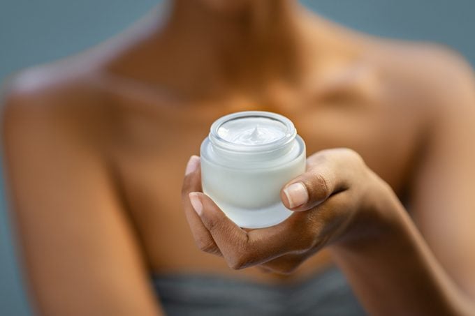 close up of woman holding moisturizer lotion in jar