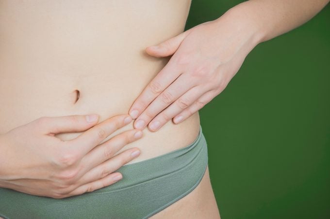 close up of woman's hands on bowel area on green background