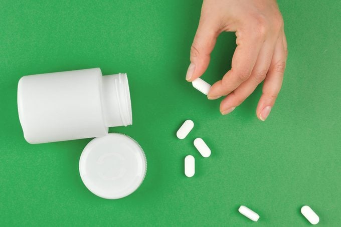 pills and pill bottle on green background