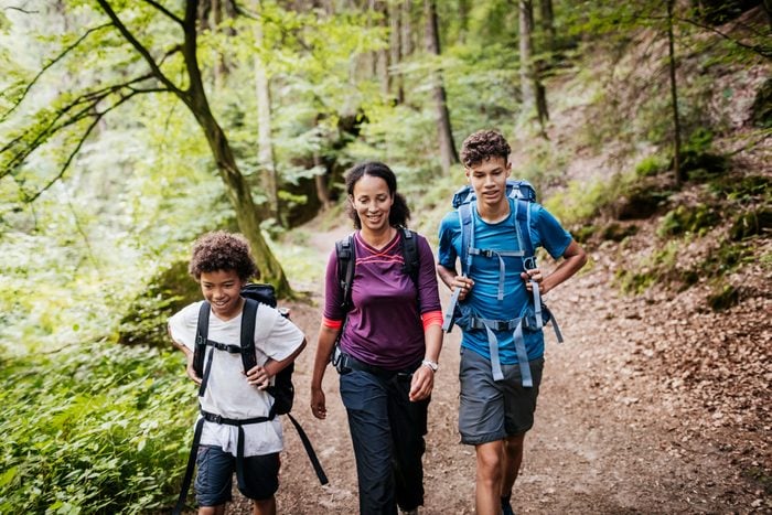 family of three hiking on a woodland trail