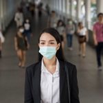 Asian woman with protective face mask in the urban bridge in city against crowd of people