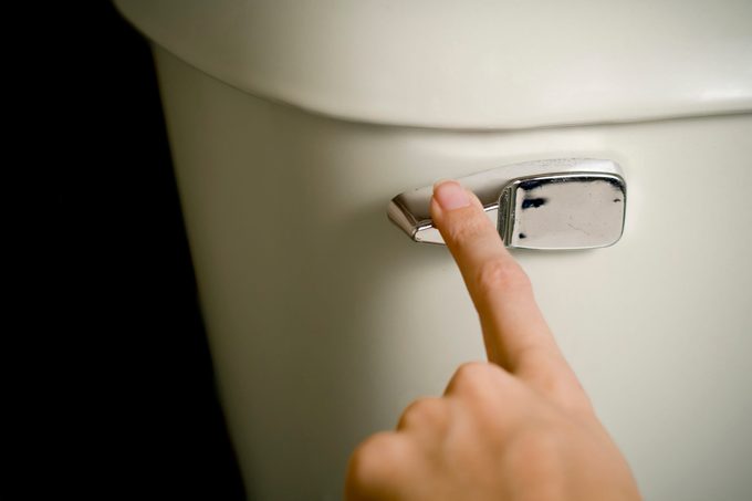 close up of finger on toilet flush