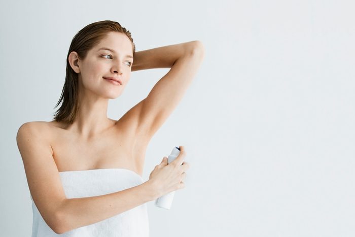 woman applying deodorant in bath towel
