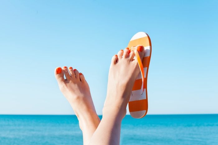 woman's feet at the beach with flip flops