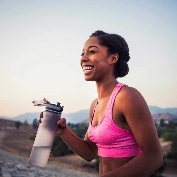 smiling female runner holding water bottle
