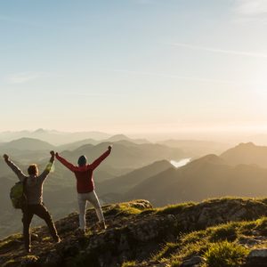couple on top of mountain with hands up