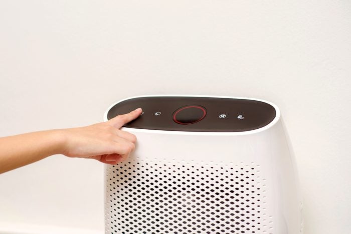 hand turning on air purifier in home