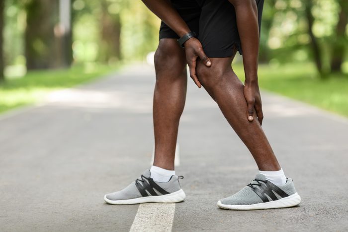 close up of man with pain in leg while exercising outside