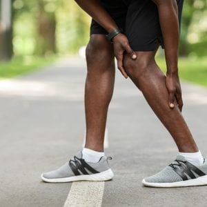 close up of man with pain in leg while exercising outside