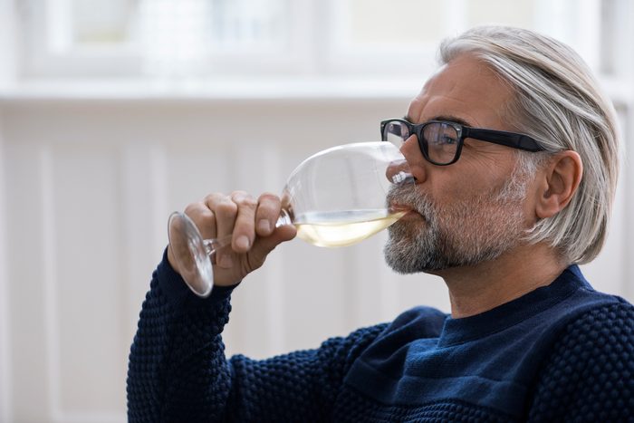 Mature man with glasses drinking white wine