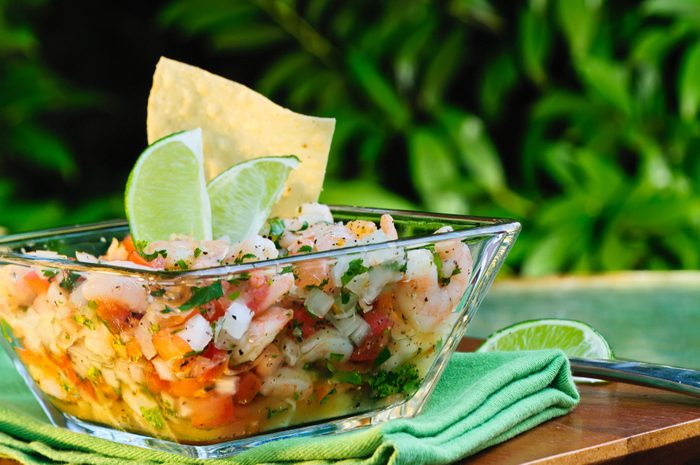 Ceviche in a bowl with lime on a wooden table