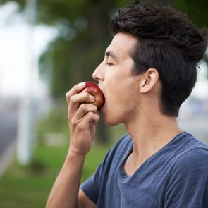 young man taking a bite into an apple
