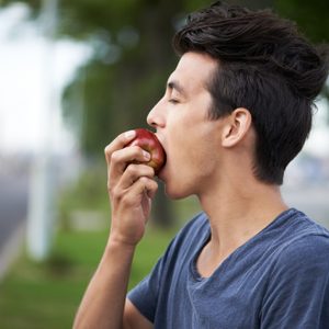 young man taking a bite into an apple