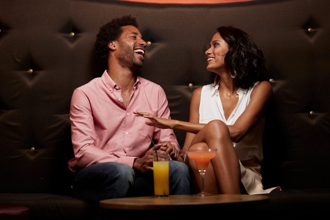 Cheerful couple conversing on sofa at nightclub