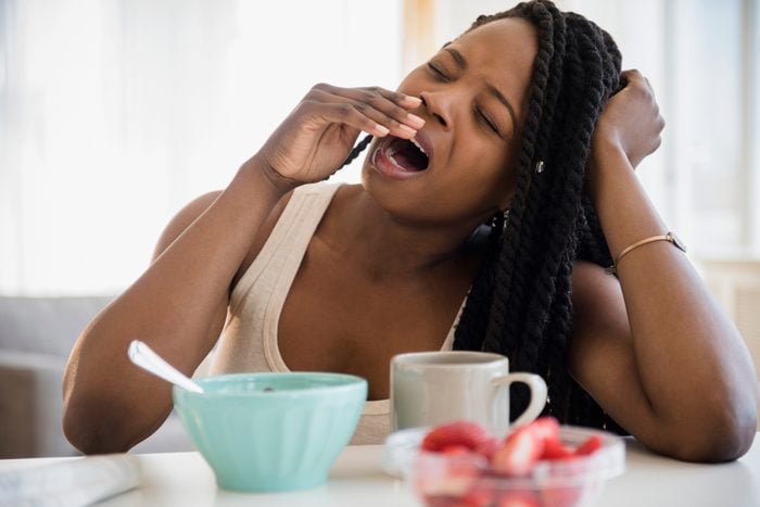 woman yawning at table