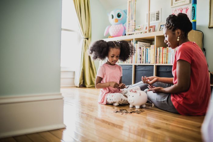 mother teaching daughter about money with piggy bank