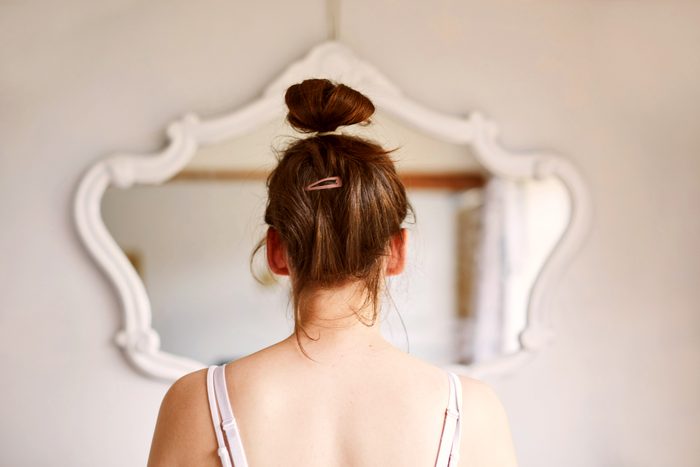 rear view of young woman looking in the mirror