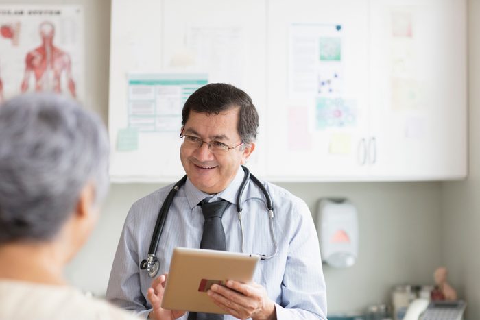 doctor with digital tablet talking to patient