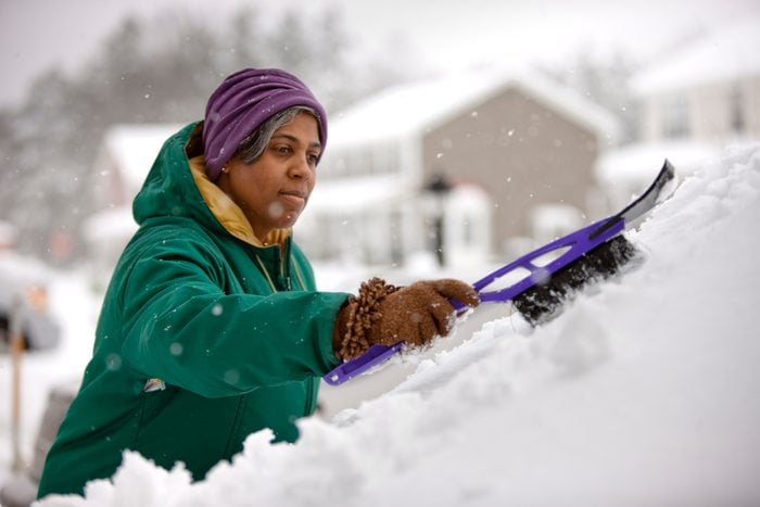 woman scraping snow from windshield