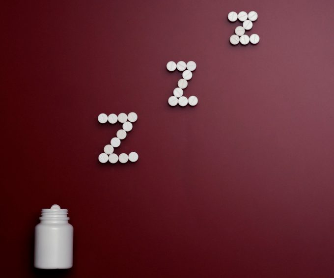 pill bottle and pills in zzz formation on dark red background