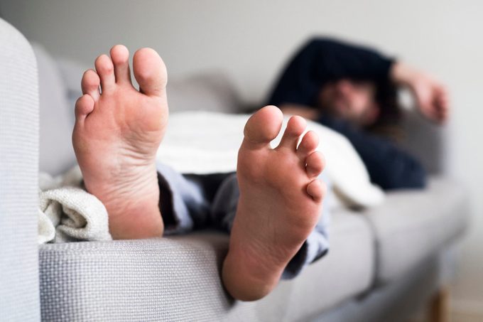 Man sleeping on sofa, close-up of feet