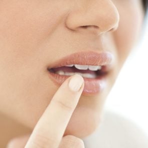 close up of woman with her finger on mouth area