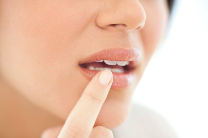 close up of woman with her finger on mouth area