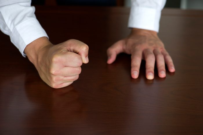 Businessman pounding fist on table, cropped