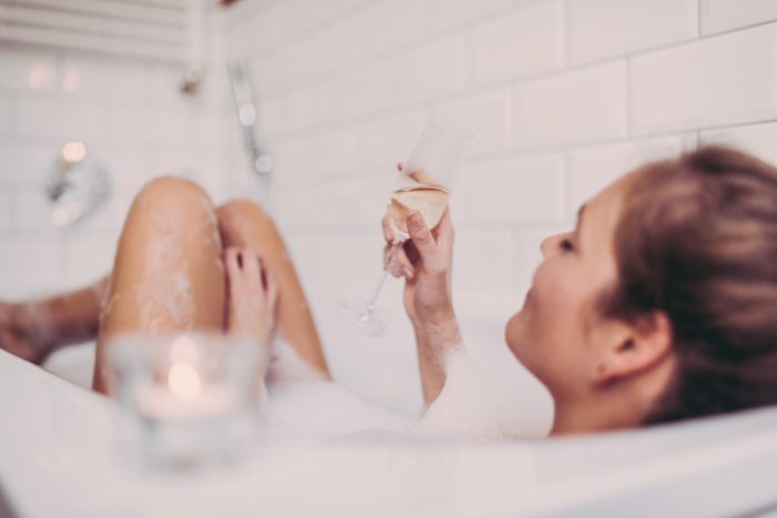 Woman enjoying a bubble bath with a glass of champagne