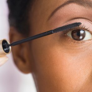 African American woman applying mascara