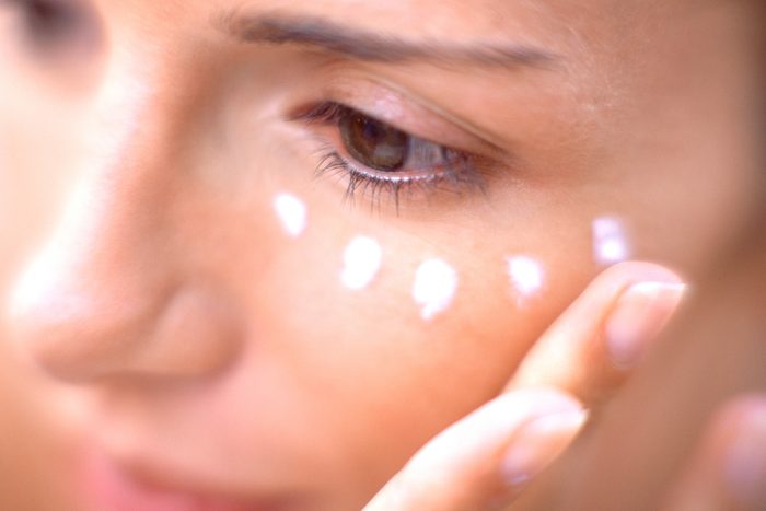 Woman applying moisturiser on face