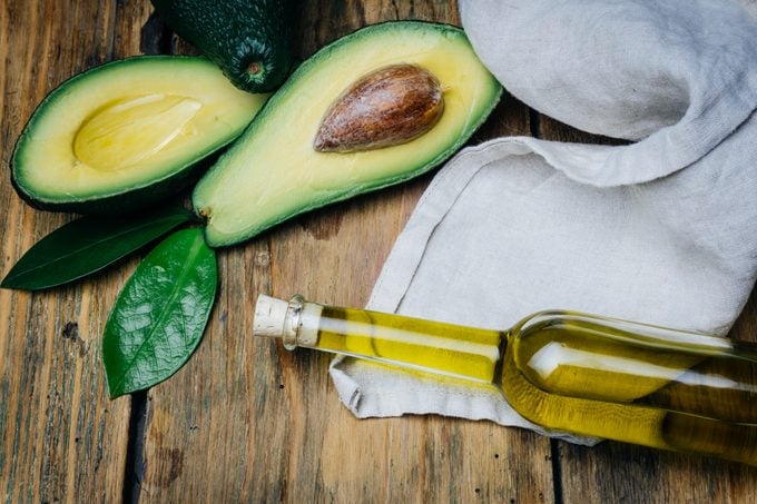 Avocado and avocado oil on a wooden background.