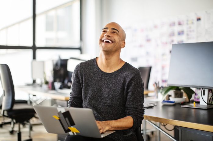 Businessman laughing with a laptop in office