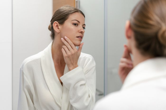 Woman in bathrobe looking in mirror at bathroom