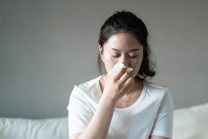 woman using a tissue to sneeze or blow her nose