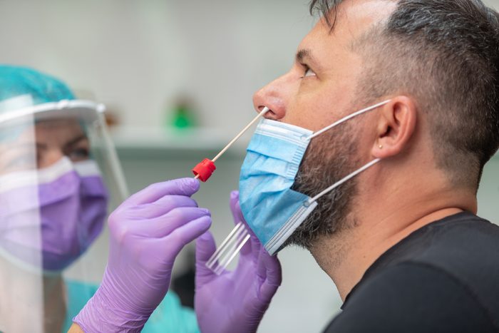 health care worker wearing protective gear taking nose swab test