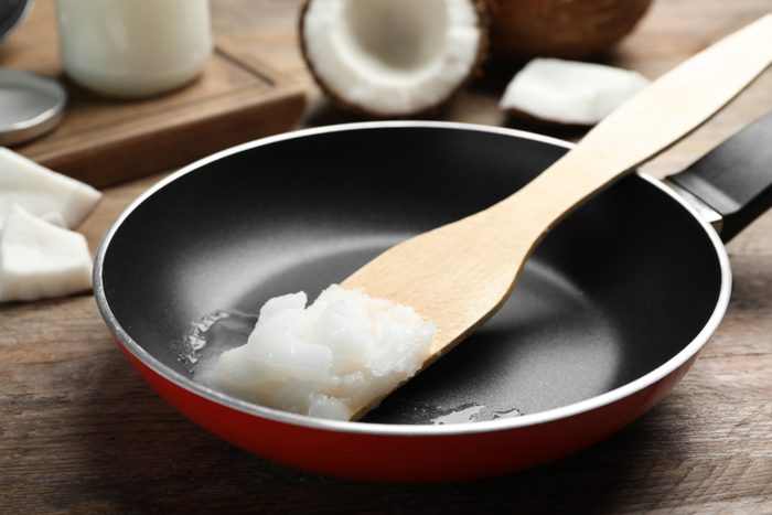 Frying pan with coconut oil and wooden spatula