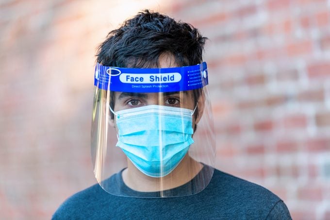 Young man wearing a face shield and a protective mask