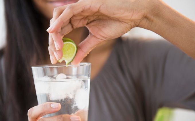 Mixed race woman squeezing lime into drink