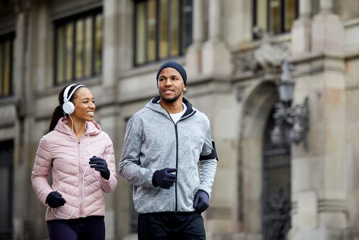 Smiling young couple talking while jogging in city