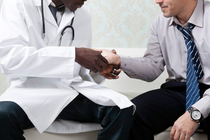 Doctor examining hand to a patient
