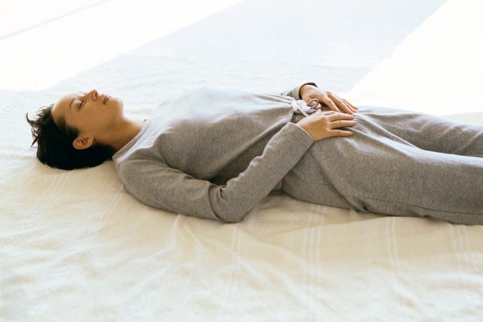 Woman wearing athletic wear lying on back with hands placed on lower abdomen