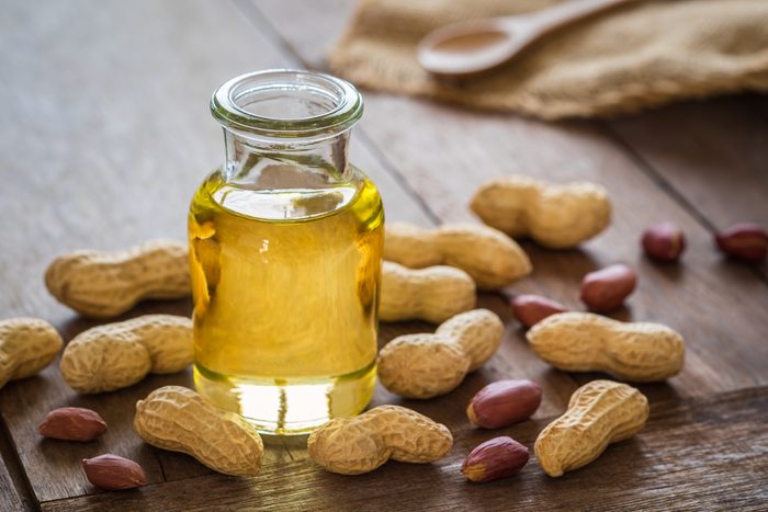 Peanut oil in glass bottle and peanuts 
