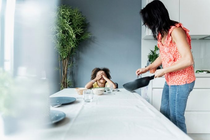 Mother serving meal for daughter sitting at dining table